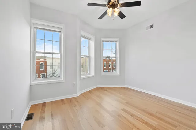 a view of empty room with wooden floor and fan