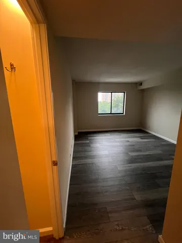 a view of hallway with window and wooden floor