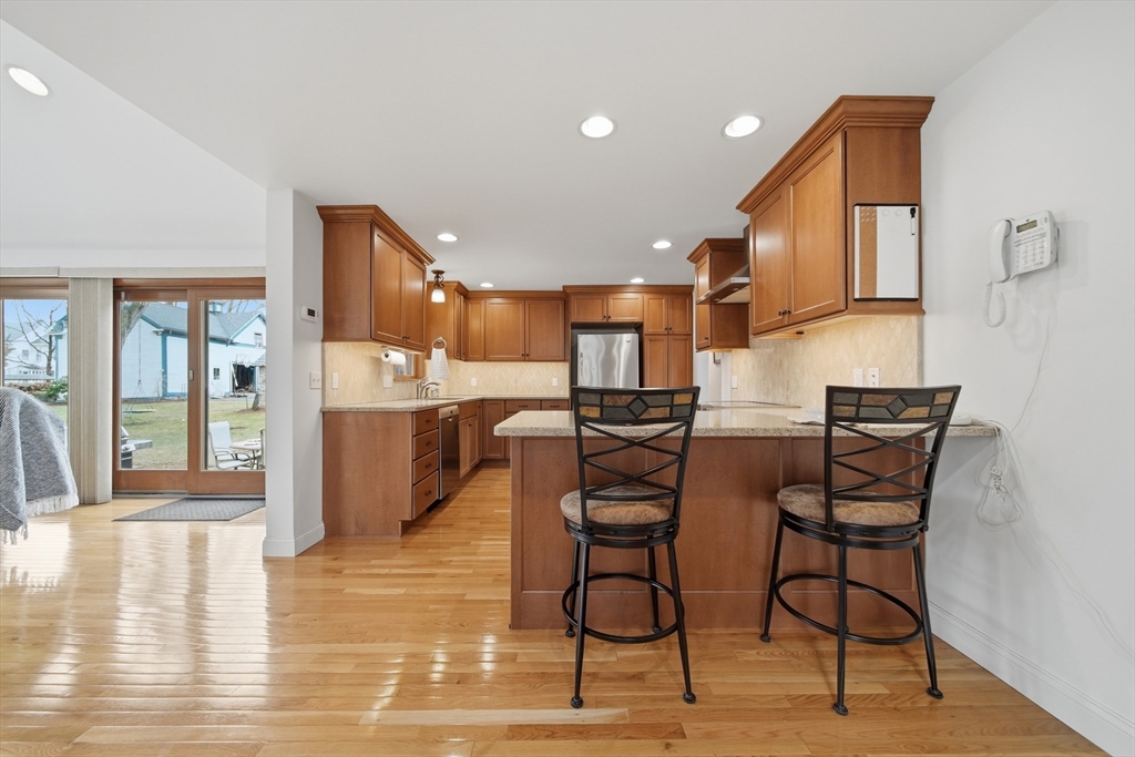 11 Lawrence Street Wakefield, MA 01880 - Photo 5 of 42 a kitchen with stainless steel appliances kitchen island granite countertop a table chairs in it and wooden floors