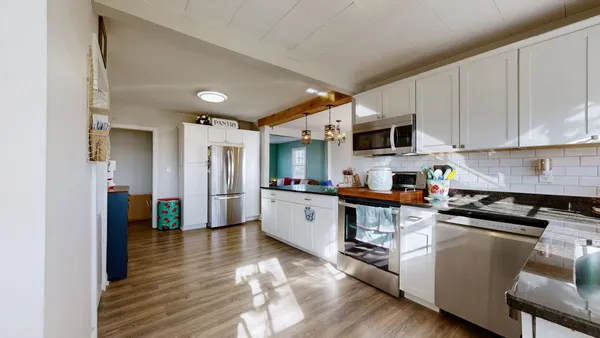 a kitchen with cabinets wooden floor and a refrigerator