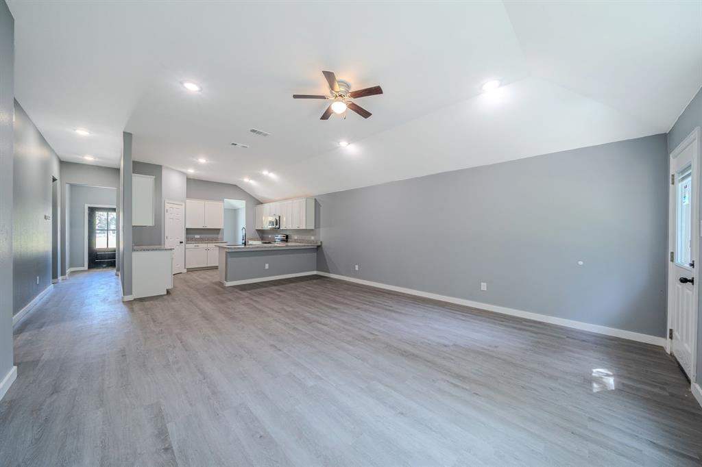 110 Red Oak Mabank, TX 75156 - Photo 4 of 30 a view of a livingroom with a kitchen island wooden floor and a ceiling fan