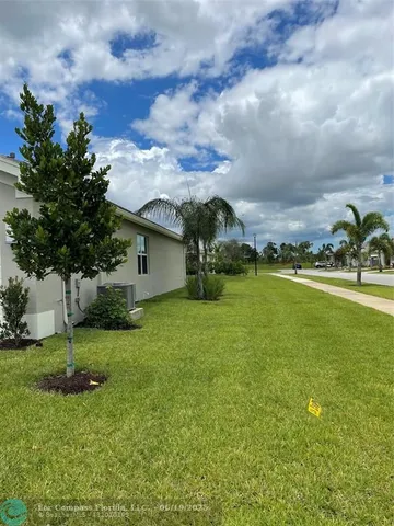 a view of a house with a big yard and a large tree