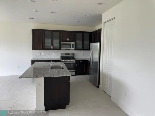 a kitchen with stainless steel appliances granite countertop a refrigerator and a stove top oven