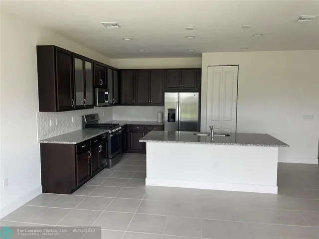 a kitchen with kitchen island a counter top space cabinets and stainless steel appliances