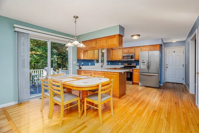 a kitchen with stainless steel appliances granite countertop a sink a stove a refrigerator with a dining table and chairs