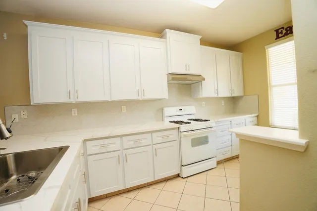 a kitchen with granite countertop white cabinets and white appliances