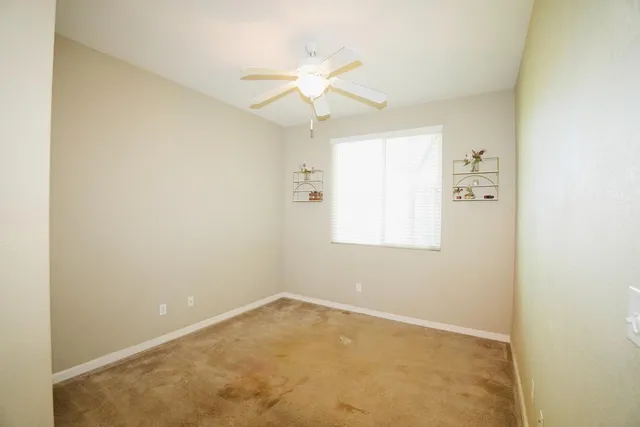 an empty room with a window and a fan