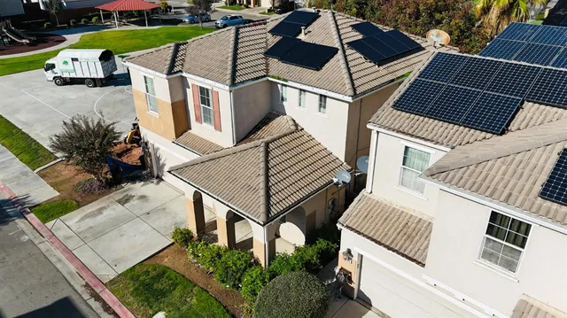 a view of a white house with large trees and wooden fence