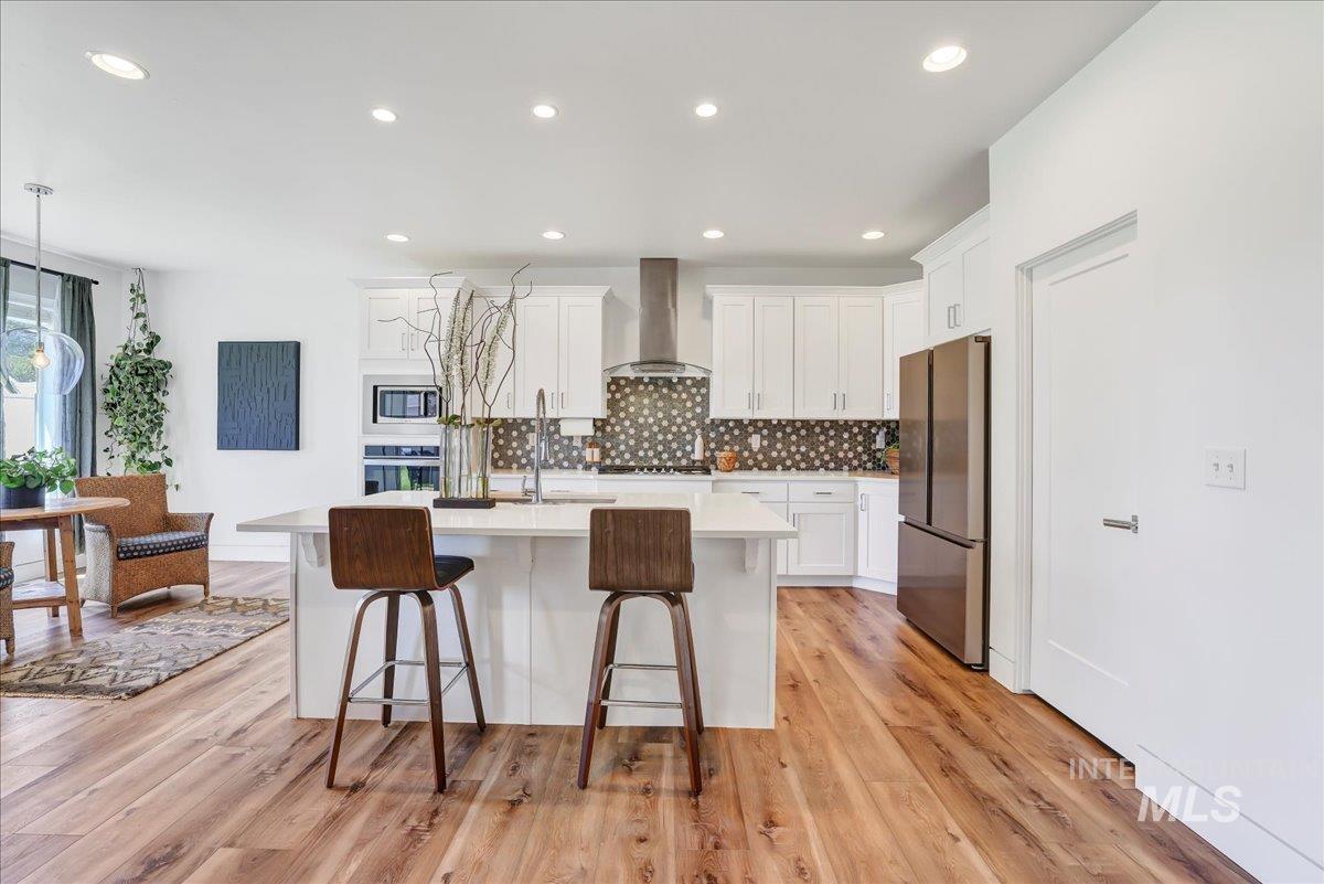 957 Birchton Loop Twin Falls, ID 83301 - Photo 11 of 32 Kitchen with a kitchen breakfast bar, backsplash, light countertops, stainless steel appliances, and white cabinetry