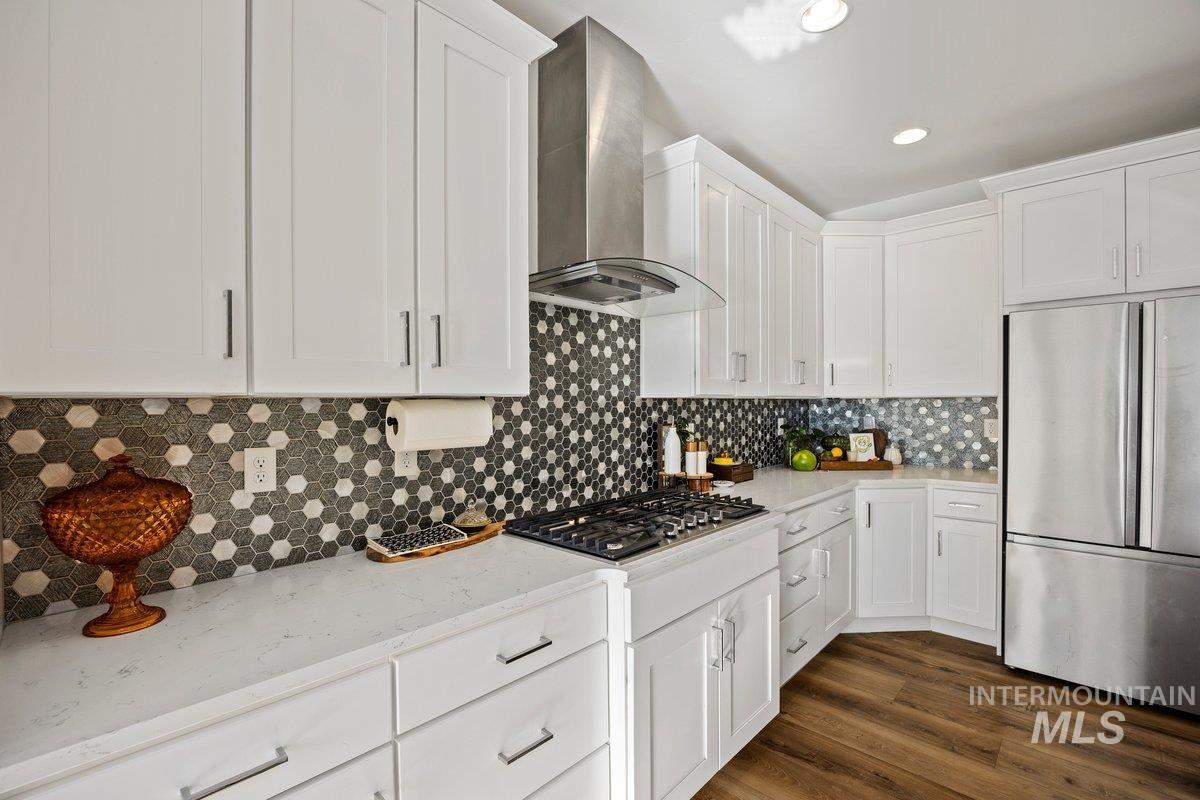 957 Birchton Loop Twin Falls, ID 83301 - Photo 13 of 40 Kitchen with white cabinets, stainless steel appliances, wall chimney exhaust hood, light stone countertops, and recessed lighting
