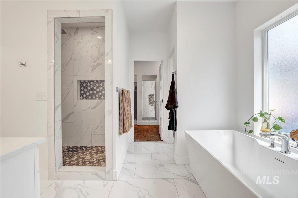 957 Birchton Loop Twin Falls, ID 83301 - Photo 19 of 32 Full bathroom featuring marble look tiles, a freestanding tub, and a marble finish shower
