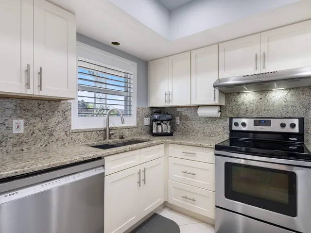 a kitchen with granite countertop white cabinets stainless steel appliances and a sink