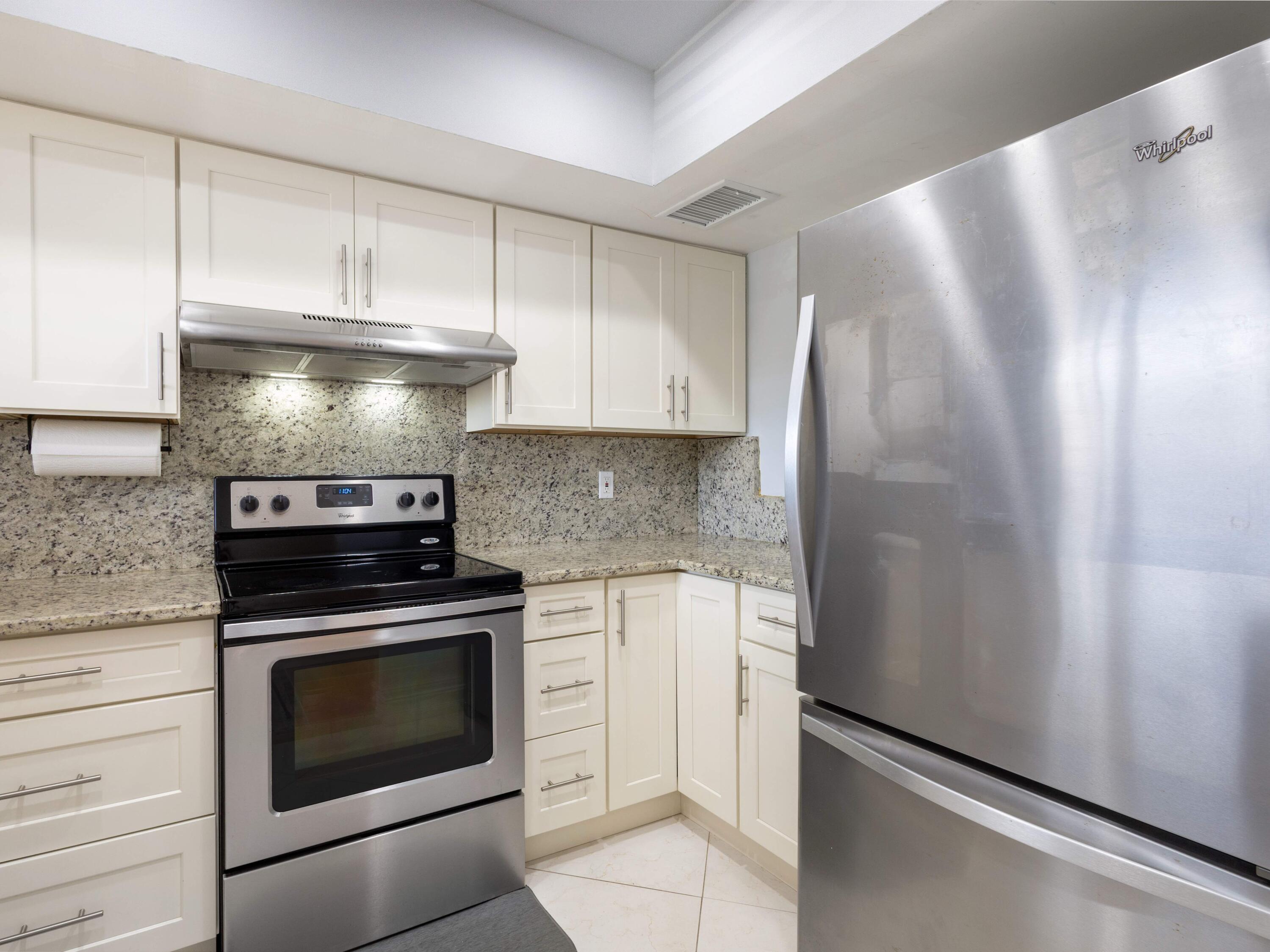 701 Harbour Drive, Unit 2140 Boca Raton, FL 33431 - Photo 8 of 35 a kitchen with granite countertop white cabinets and stainless steel appliances