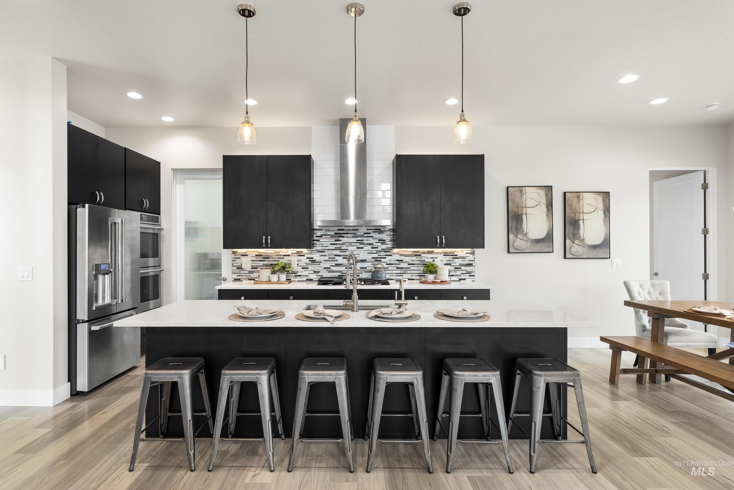 3672 West Red Jade Court Meridian, ID 83646 - Photo 12 of 50 Kitchen with dark cabinetry, a breakfast bar area, stainless steel appliances, and decorative light fixtures