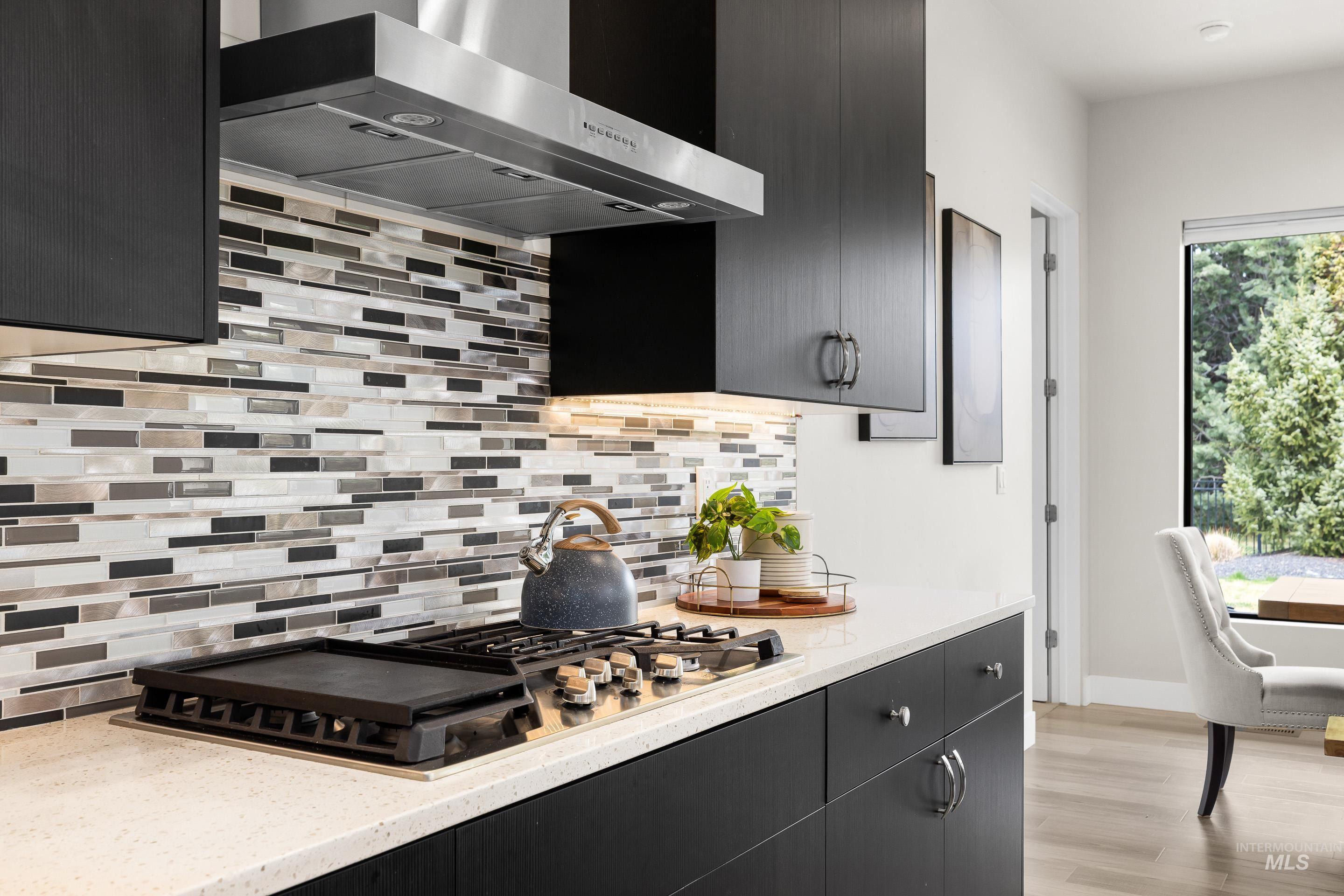 3672 West Red Jade Court Meridian, ID 83646 - Photo 15 of 50 Kitchen featuring ventilation hood, stainless steel gas stovetop, backsplash, and dark cabinets