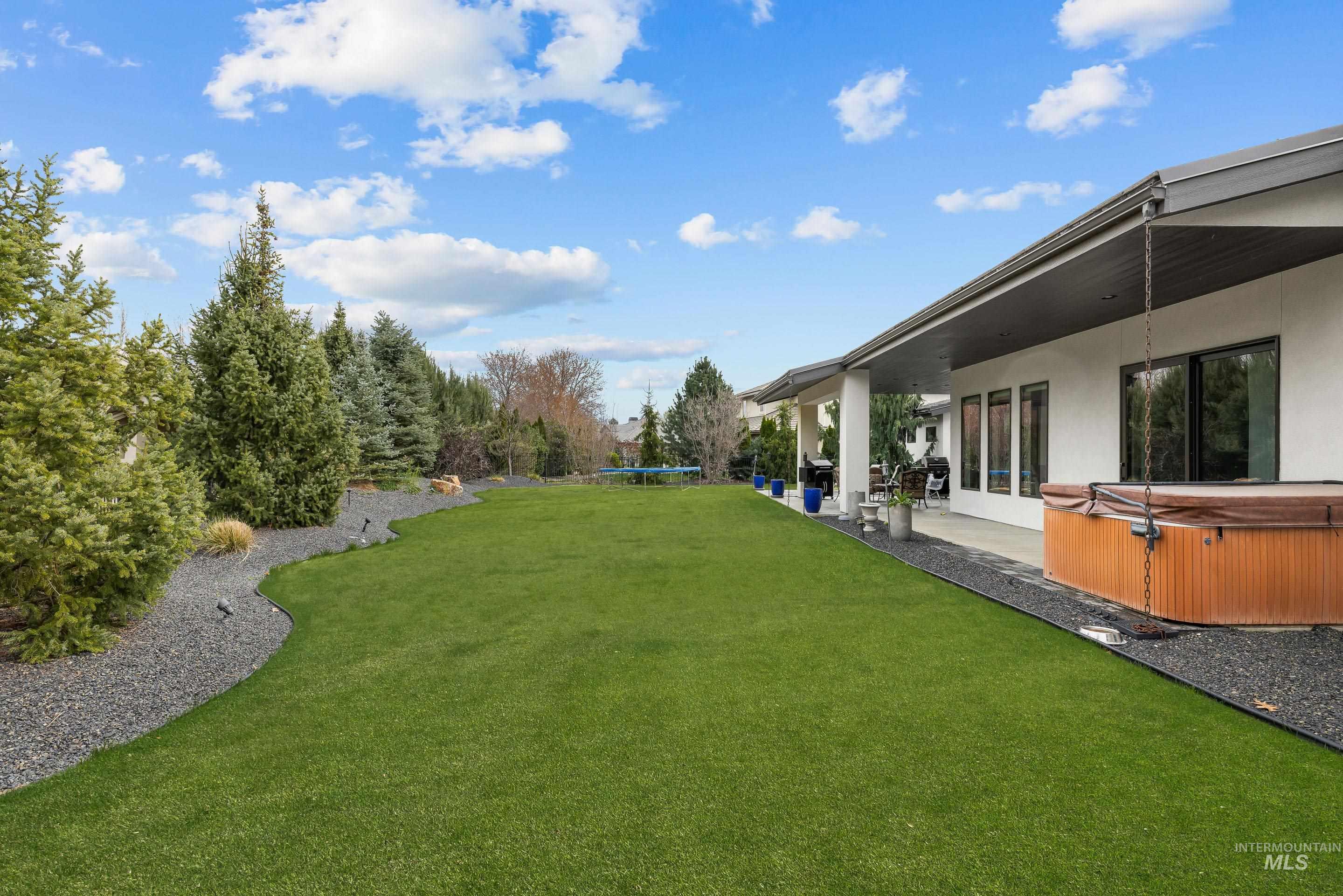 3672 West Red Jade Court Meridian, ID 83646 - Photo 32 of 50 View of grassy yard with a trampoline, a hot tub, and a patio area