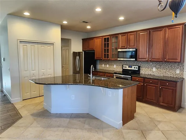 a kitchen with kitchen island granite countertop a stove a sink and a microwave