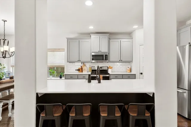 a kitchen with stainless steel appliances a table chairs refrigerator and sink
