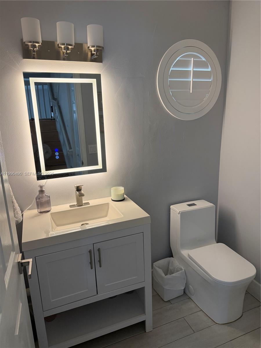 7431 Southwest 163rd Place Miami, FL 33193 - Photo 14 of 18 a bathroom with a toilet sink vanity and mirror