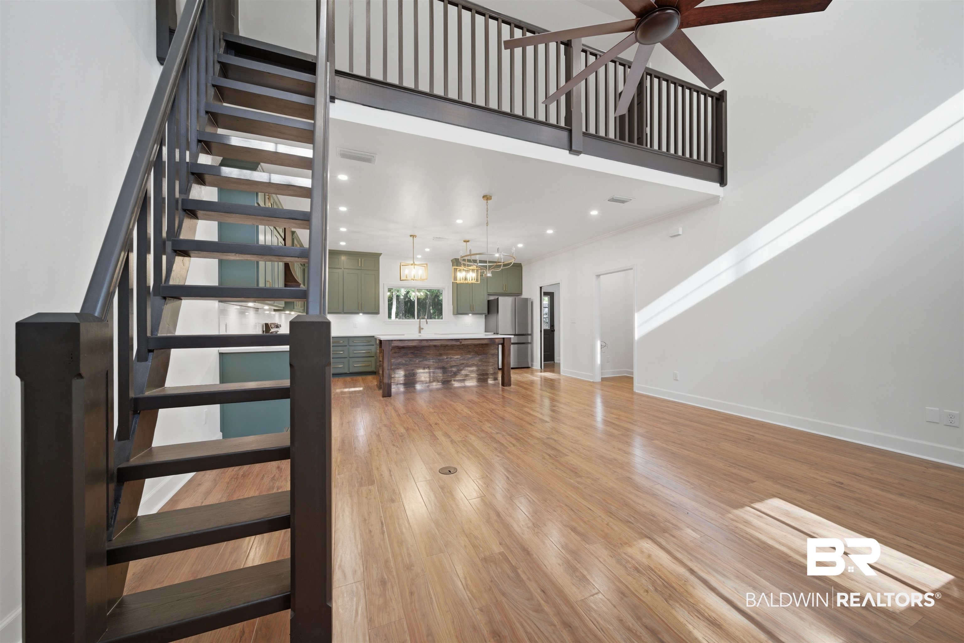 14128 Jackson Lane Foley, AL 36535 - Photo 17 of 36 Open-concept living area featuring wood-finish flooring, a contemporary dark wood staircase, and a lofted space with a matching railing