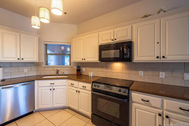 a kitchen with granite countertop a stove top oven microwave and cabinets