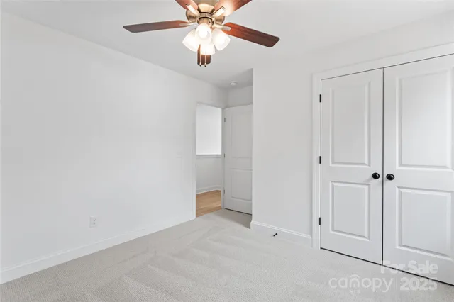 an empty room with closet and a chandelier fan