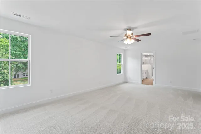 an empty room with windows and chandelier fan