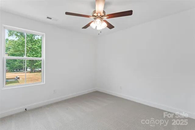 an empty room with a window and a fan