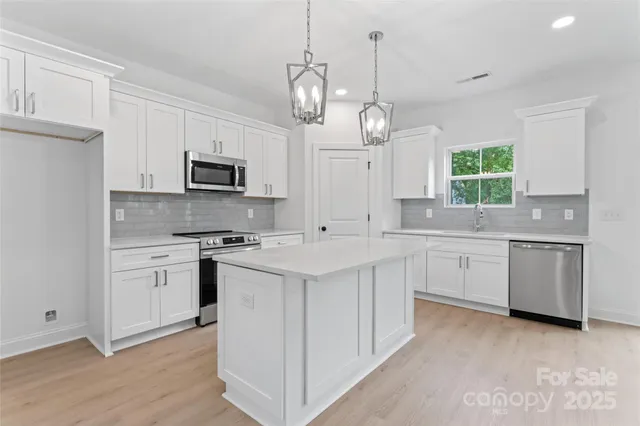 a kitchen with white cabinets stainless steel appliances and window