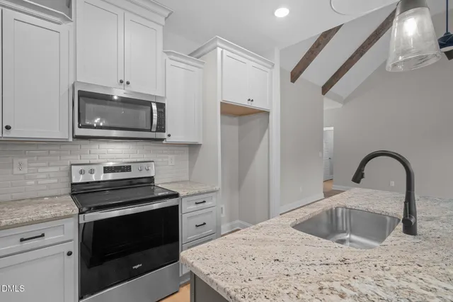 a kitchen with stainless steel appliances granite countertop a stove microwave and a sink