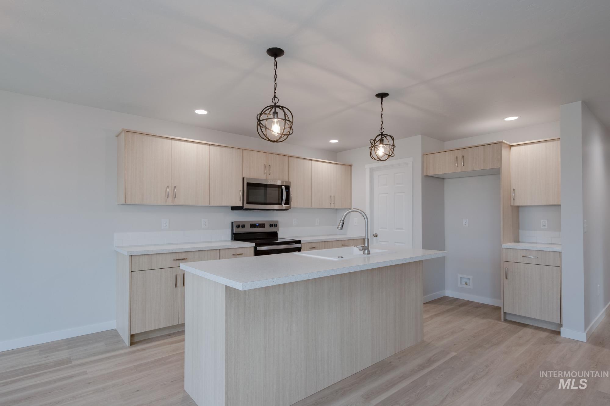 3089 South Maple Rnch Way Nampa, ID 83686 - Photo 10 of 22 Kitchen with stainless steel appliances, light countertops, pendant lighting, light brown cabinetry, and light wood finished floors