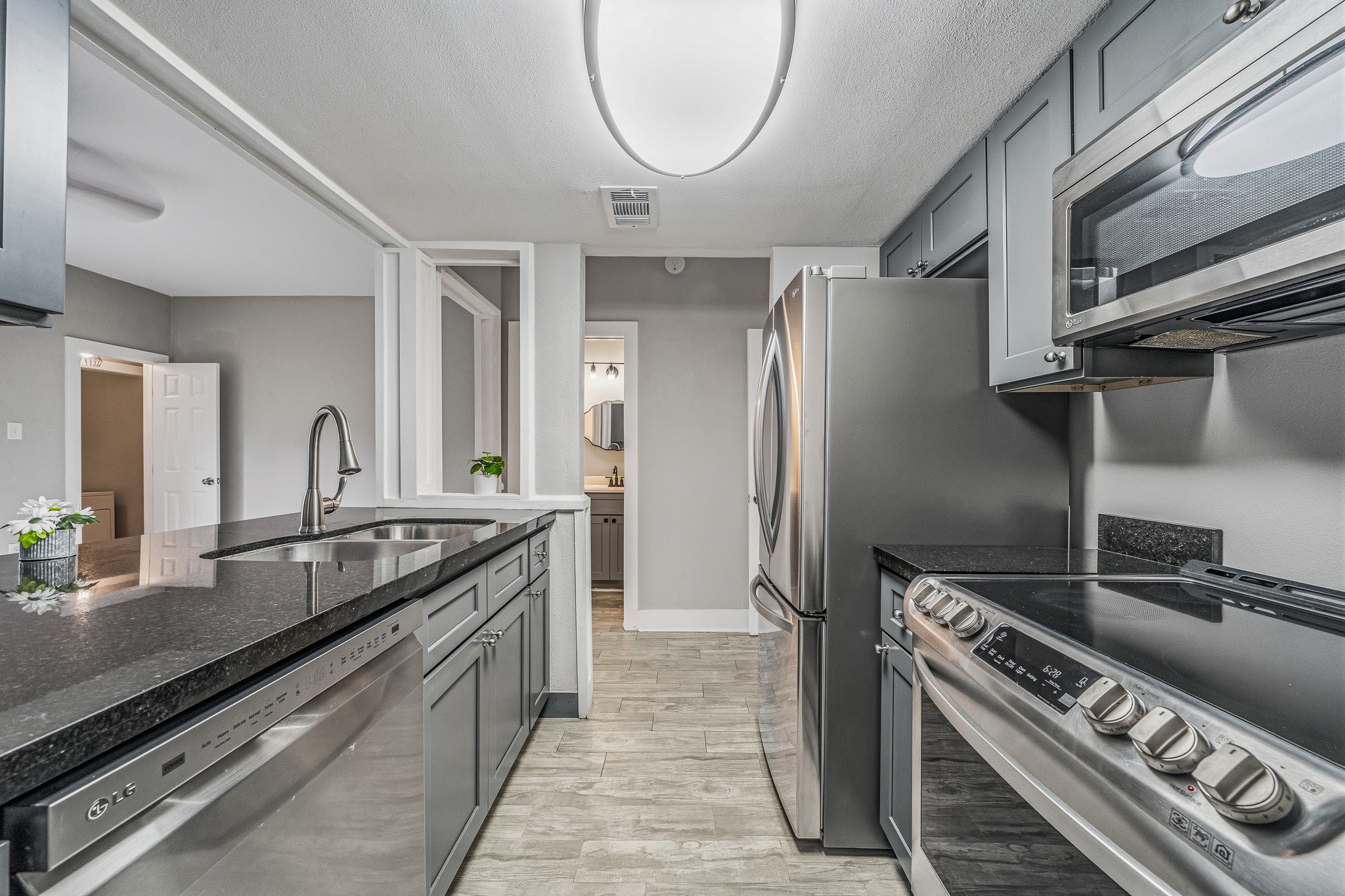 830 Threadneedle Street, Unit 240 Houston, TX 77079 - Photo 10 of 33 This modern kitchen features sleek stainless steel appliances, grey cabinetry, and dark countertops. The layout is efficient with ample storage and a double sink. It opens to a bright living area, enhancing the open-concept feel.