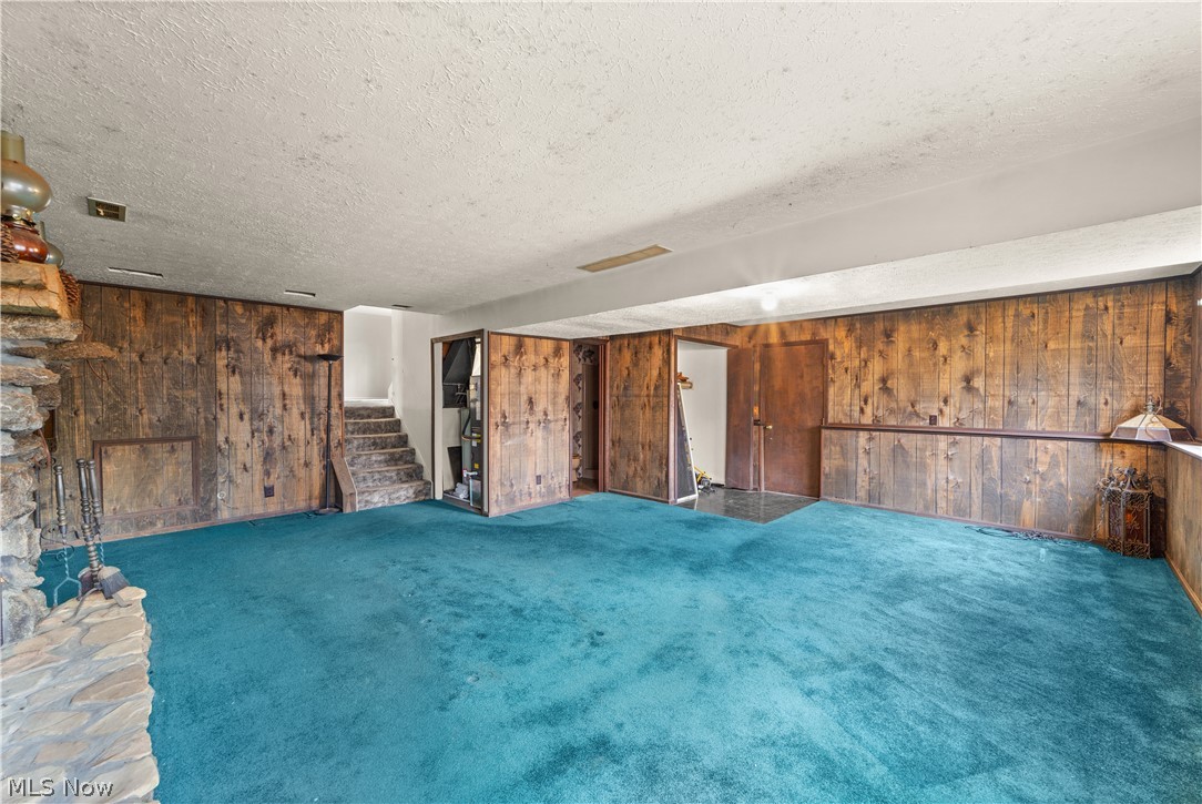 18763 Sharon Road Chagrin Falls, OH 44023 - Photo 25 of 37 Family room with wooden walls, a textured ceiling, and dark carpet