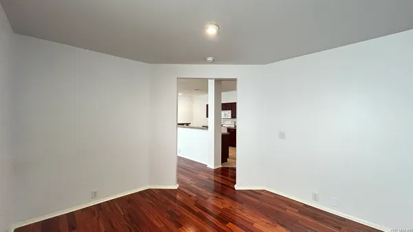 an empty room with wooden floor and entrance