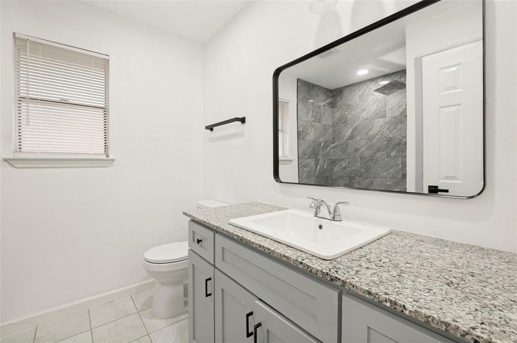 2908 Legend Road Arlington, TX 76014 - Photo 26 of 29 Bathroom featuring a light-toned granite countertop, a rectangular undermount sink with a chrome faucet, and gray shaker-style vanity cabinets with black hardware