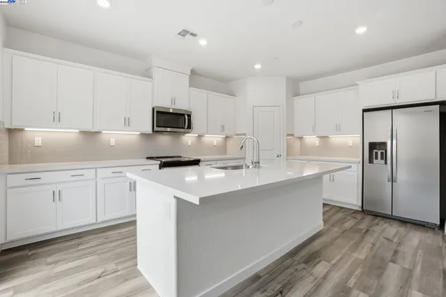 a kitchen with a sink a stove a refrigerator and white cabinets