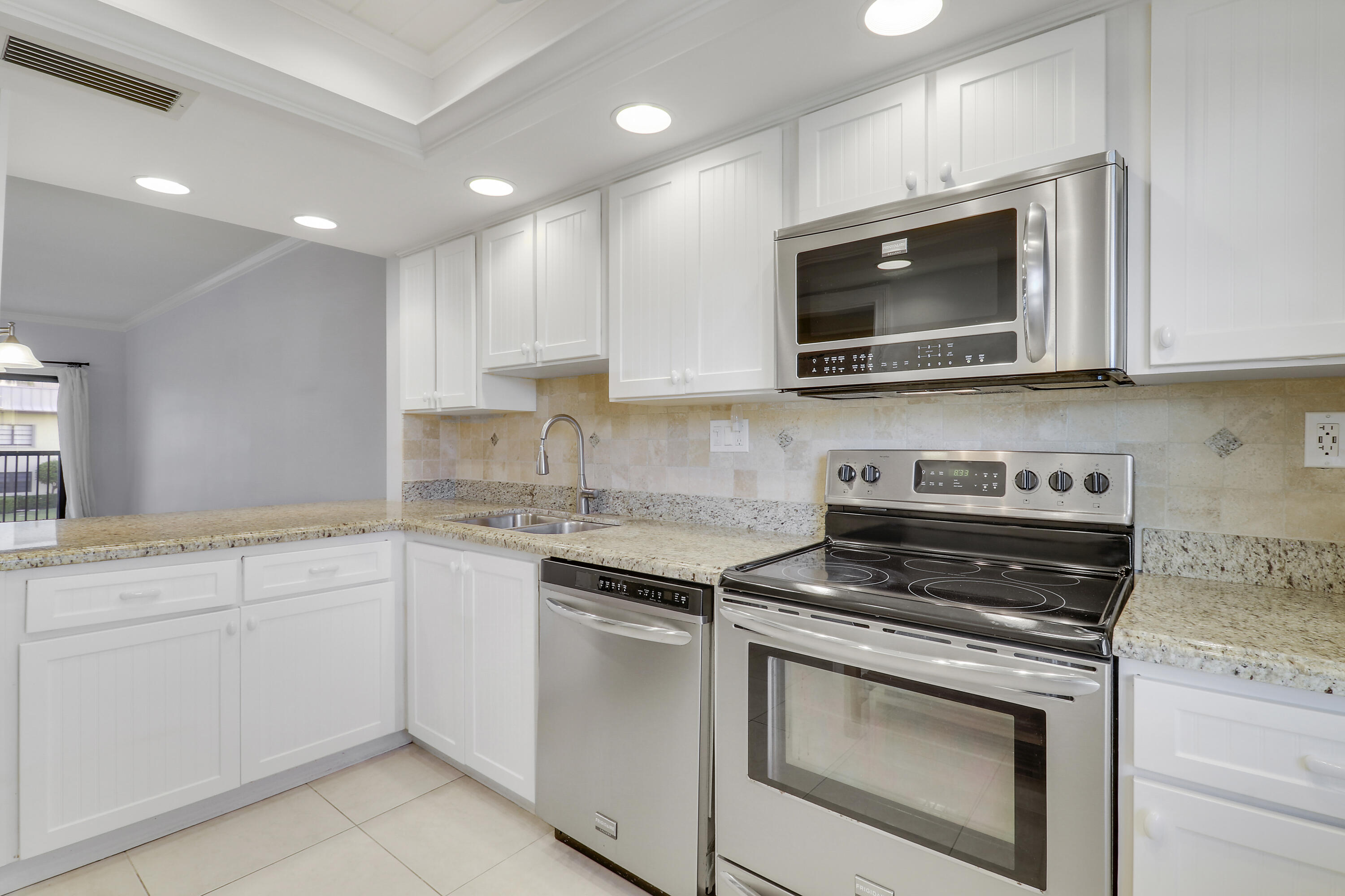 275 South Beach Road, Unit B202 Tequesta, FL 33469 - Photo 23 of 37 a kitchen with white cabinets and stainless steel appliances