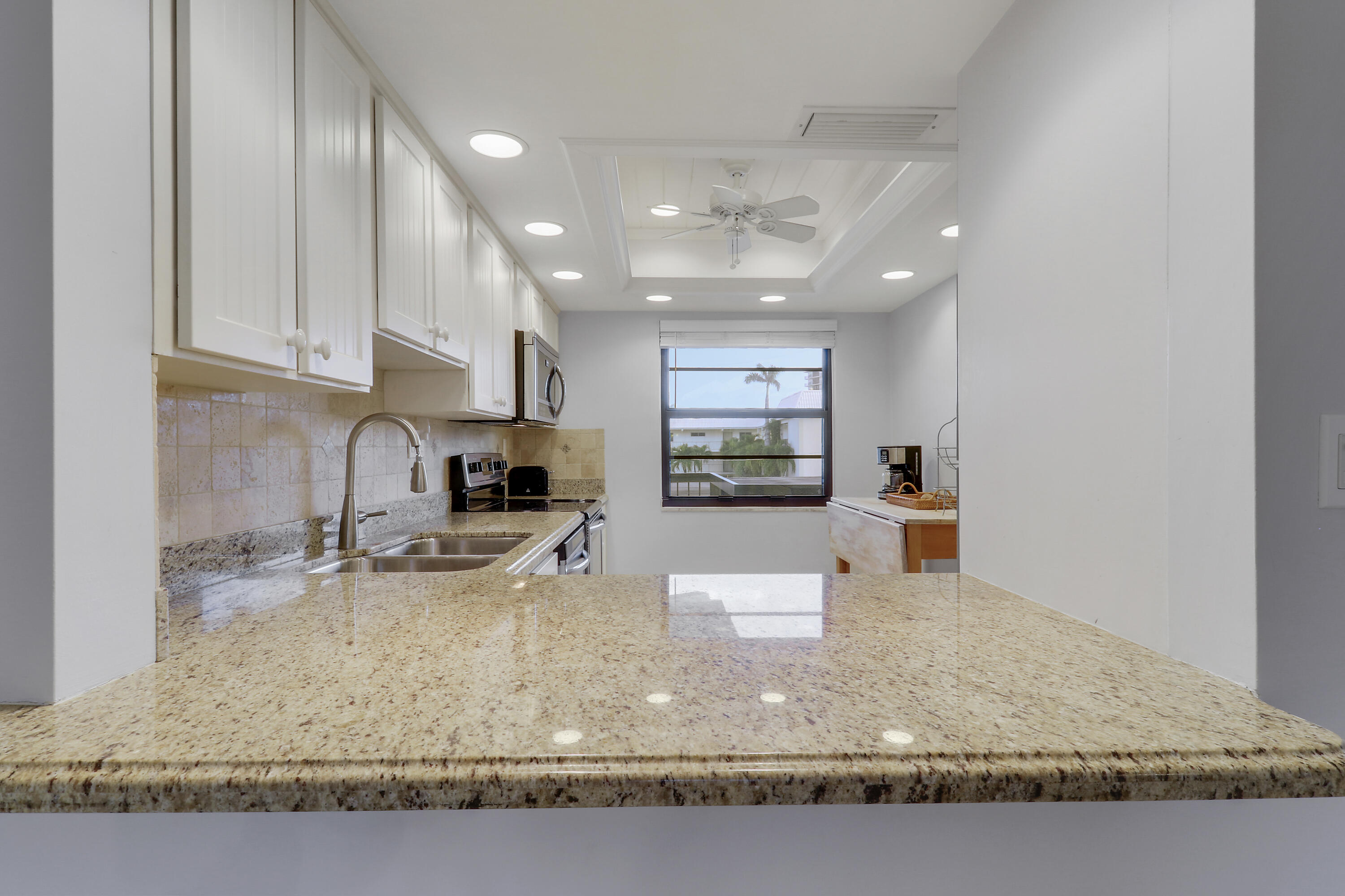 275 South Beach Road, Unit B202 Tequesta, FL 33469 - Photo 29 of 37 a kitchen with kitchen island granite countertop a sink window and refrigerator