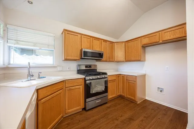 a kitchen with granite countertop wooden cabinets stainless steel appliances and a window