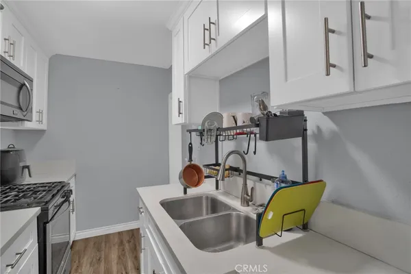 a kitchen with sink and a stove with wooden floor