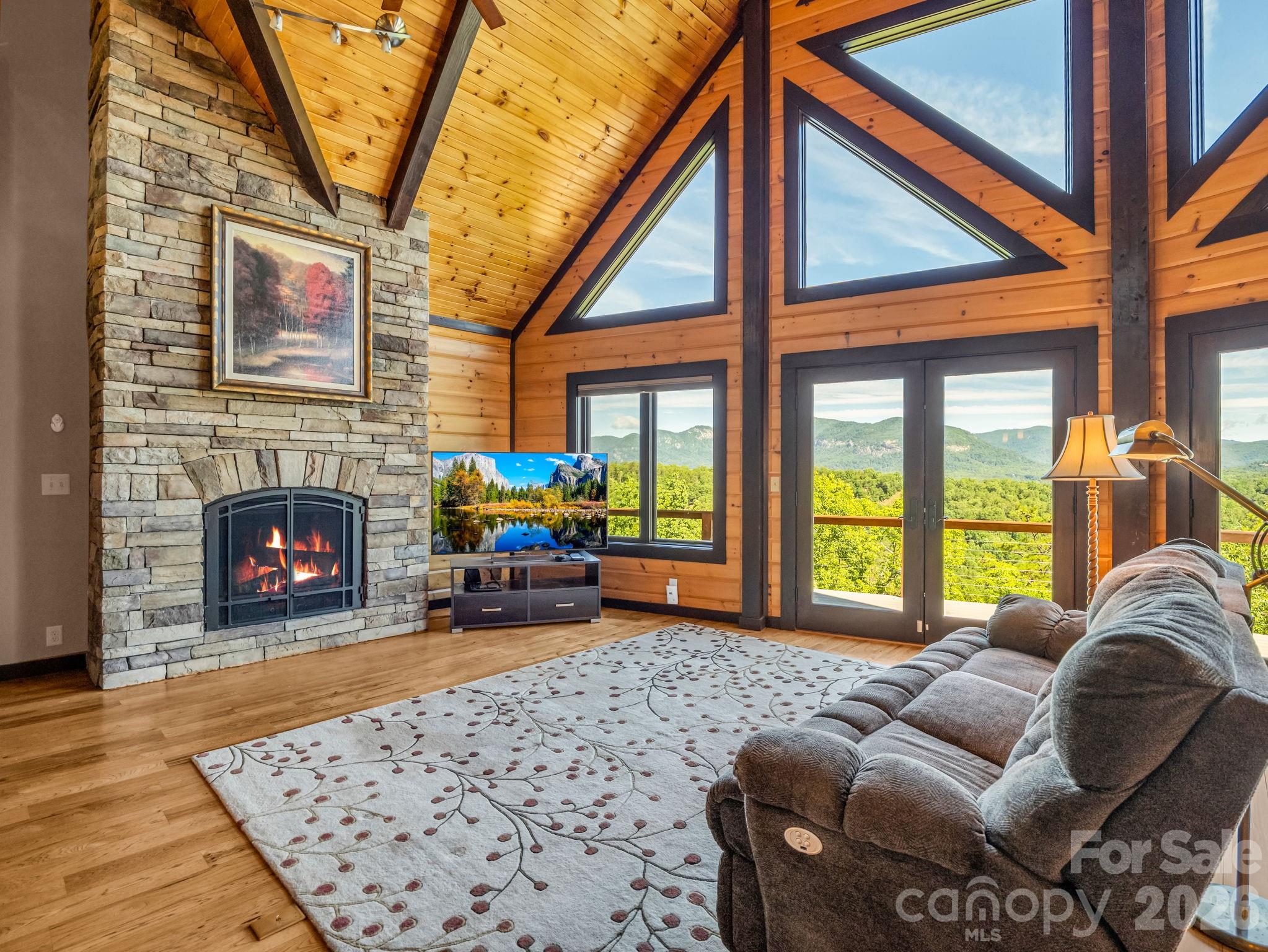 590 Boulder Ridge Lake Lure, NC 28746 - Photo 10 of 48 a living room with furniture a fireplace and a floor to ceiling window