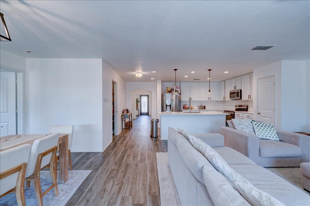 6233 Skysail Road Fort Worth, TX 76179 - Photo 15 of 30 a view of a kitchen with kitchen island stainless steel appliances refrigerator stove a dining table and chairs with wooden floor