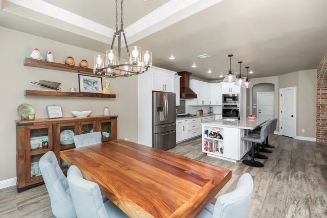 a large kitchen with kitchen island stainless steel appliances a table chairs sink and cabinets