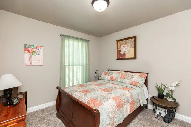 a bedroom with a bed and a lamp on dresser