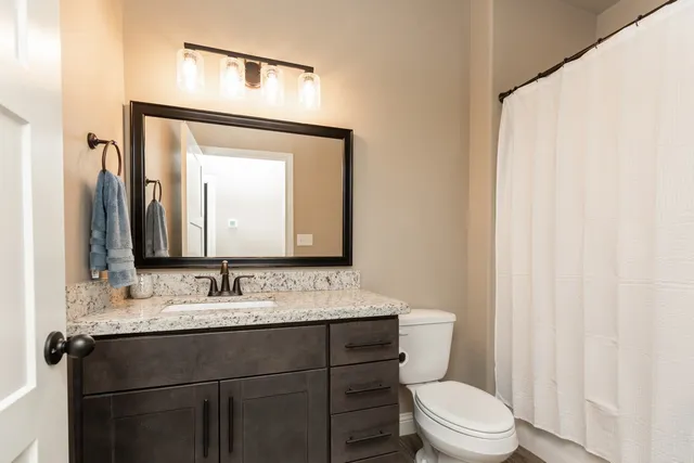 a bathroom with a toilet sink vanity and mirror