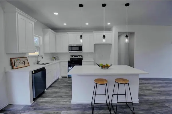 a kitchen with kitchen island a wooden floor and white appliances