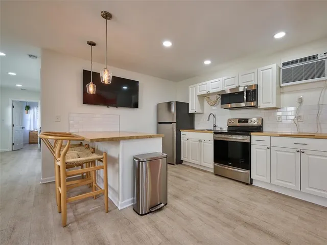 a kitchen with stainless steel appliances white cabinets a stove a microwave and a refrigerator