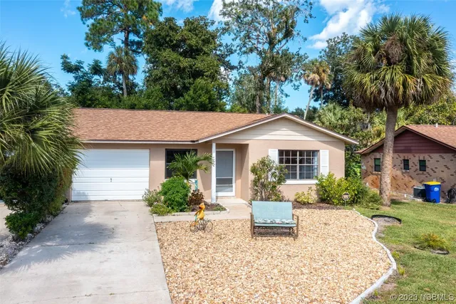 a front view of a house with a yard and potted plants