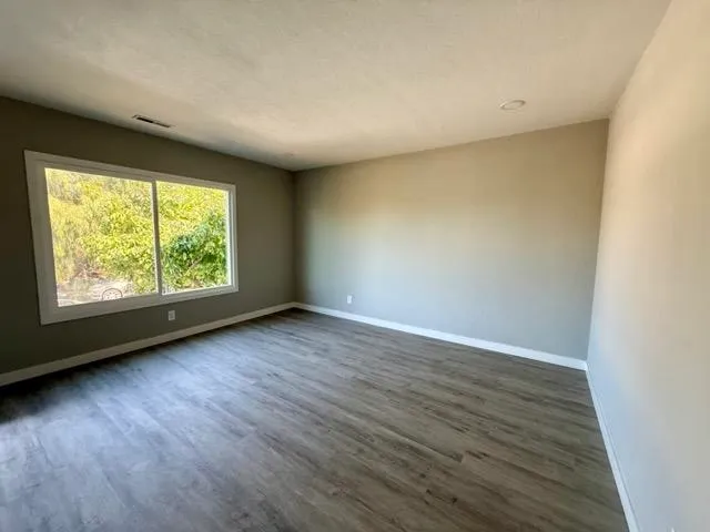 an empty room with wooden floor and windows