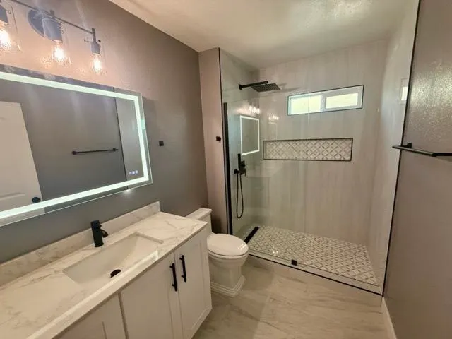 a bathroom with a double vanity sink toilet mirror and shower